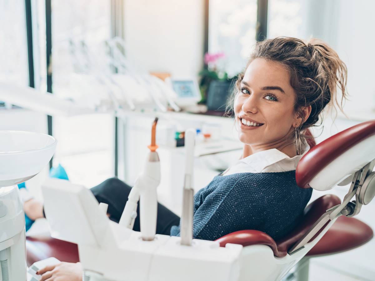 Frau sitzt auf dem Behandlungsstuhl und lächelt